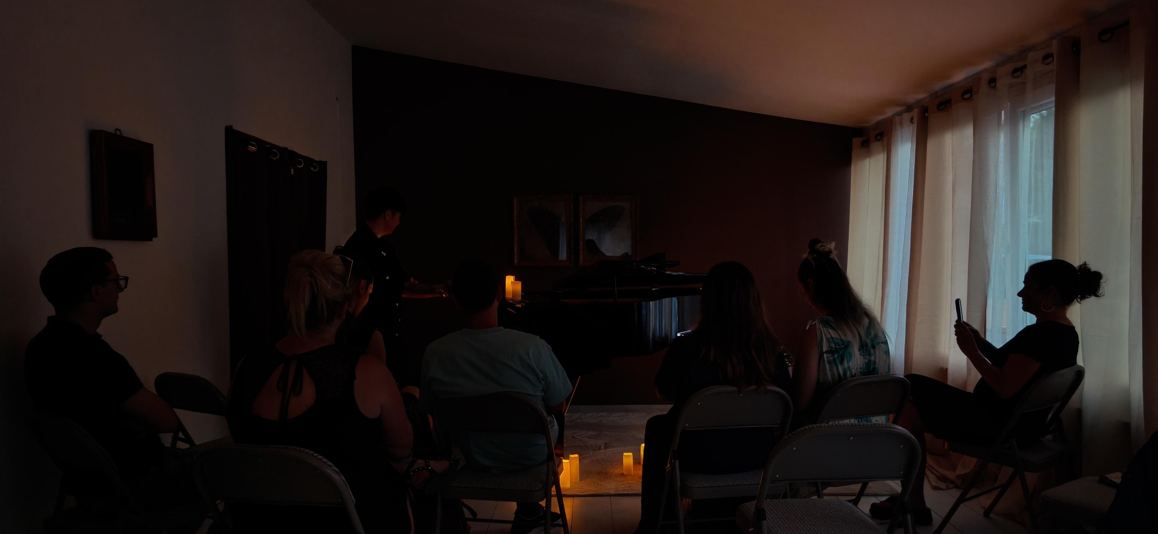 Public assis en cercle autour du piano, éclairage aux bougies